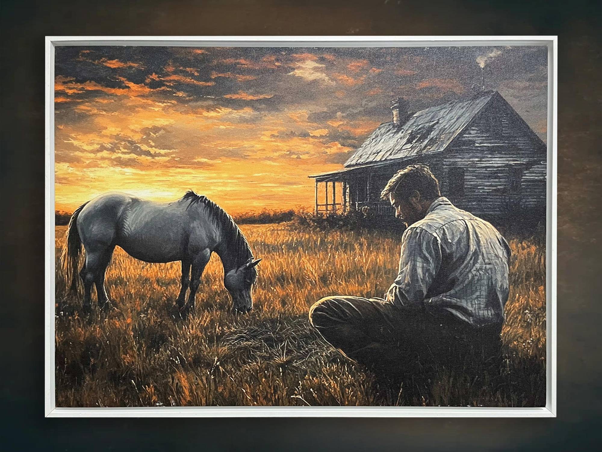 A man kneeling in a golden field at sunset, facing a grazing horse before a weathered farmhouse.
